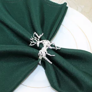 Silver metal reindeer napkin ring with dark green napkin for dining table decor and parties.