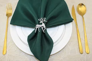 Elegant Christmas reindeer napkin ring with dark green fabric napkin for holiday table decor.