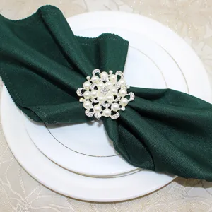 Detail shot of the elegant floral pearl rhinestone napkin ring holding a dark green fabric napkin.