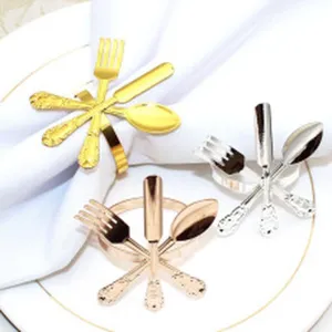Close-up detail of metal napkin rings featuring miniature cutlery design in gold and silver.