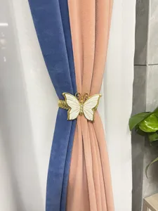 Primo piano dell'elegante fermatenda decorativo a molla in metallo con farfalla dorata.