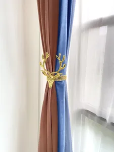 Dettaglio fermatenda a testa di cervo dorata, elegante fibbia elastica per tende.