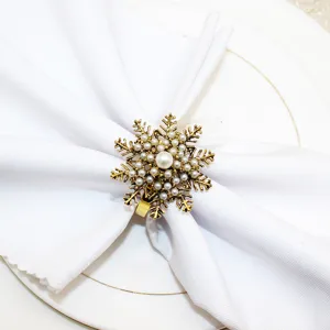 Elegant antique gold snowflake napkin ring with pearls for Christmas dinner table decor setting.