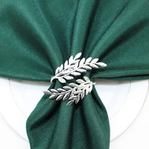 Silver metal leaf napkin ring with dark green cloth napkin for table decor detail.