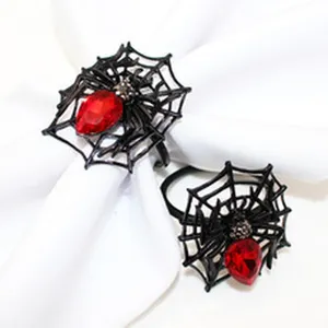 Detail view of black spider web napkin rings with red crystal drops for Halloween party decor.