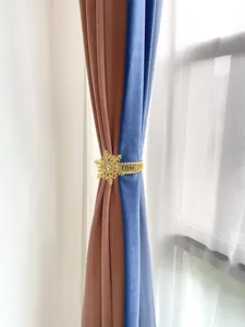 Primo piano della fibbia per tenda a fiocco di neve dorato con strass su velluto.