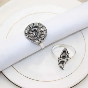 Close-up of vintage metal shell napkin rings set on white napkin and plate, table decor.