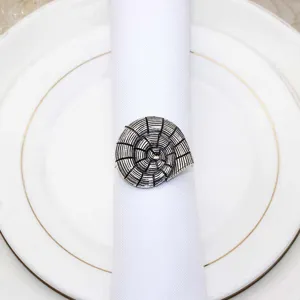 Close-up of vintage shell napkin ring on white cloth napkin, elegant table decor detail.