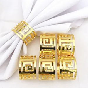 Elegant gold metal napkin rings with hollow geometric Greek key design for table decor detail view.