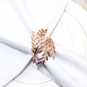 Rose gold metal leaf napkin ring detail showing elegant double branch design on clean white napkin.