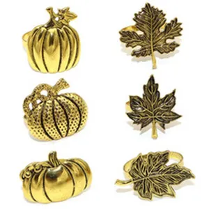 Close-up detail of vintage gold autumn maple leaf and pumpkin metal napkin ring set for decor.