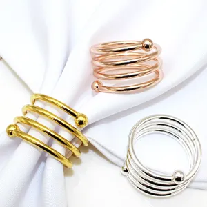 Detail view of metal spring napkin rings with double beads in gold, rose gold, and silver.