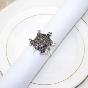 Detailed close-up view of a vintage metal turtle napkin ring on a white plate setup.