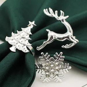 Detail view of silver metal Christmas napkin rings featuring tree, reindeer and snowflake designs.