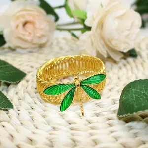 Gold metal spring curtain tieback with green enamel dragonfly, elegant home decor accessory.