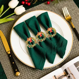 Christmas wreath napkin rings with red bells and green napkins, perfect holiday table decor.
