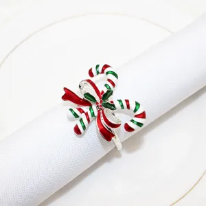 Close-up of Christmas candy cane napkin ring with red green enamel bow design on white napkin.
