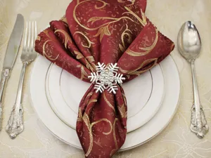 Detailed view of a silver rhinestone snowflake napkin ring with a red patterned napkin.
