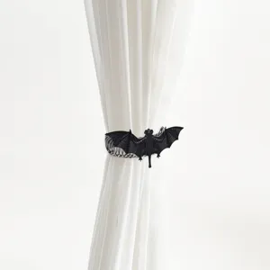 Detail shot of a gothic black bat metal spring curtain tieback holding a white sheer curtain.