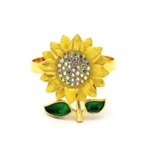Portatovaglioli con girasole dorato, foglie verdi e cristalli per decorazione tavola.