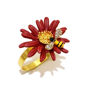 Primo piano del raffinato anello portatovagliolo con fiore rosso e ape in strass per la tavola.
