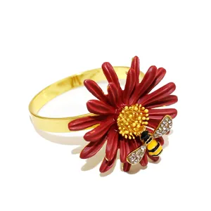 Primo piano dettagliato dell'anello per tovaglioli in metallo con petali rossi e ape di strass.