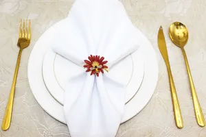 Dettaglio dell'anello portatovagliolo a fiore rosso con ape su tavola apparecchiata.