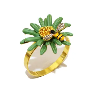 Portatovaglioli in metallo dorato con margherita verde e ape in strass per feste a tavola.
