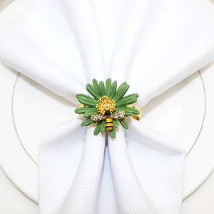Primo piano dettagliato di un portatovagliolo margherita verde con ape in strass su un tovagliolo bianco.