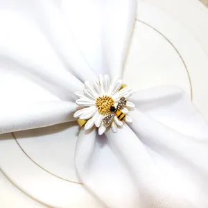 Delizioso portatovagliolo margherita bianca con ape in strass, elegante dettaglio tavola.