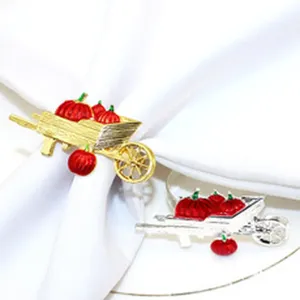 Metal wheelbarrow napkin ring with red pumpkins, Thanksgiving dinner table decor detail view.