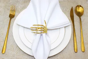 Gold skeleton hand napkin ring detail shot, elegant table setting for Halloween party.