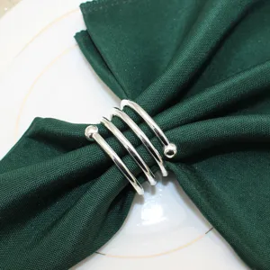 Metal napkin ring detail showing the spring design and double bead ends on a green napkin.