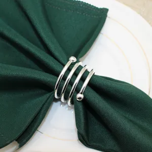 Silver metal napkin ring detail featuring a multi-loop spiral design with decorative ball ends.