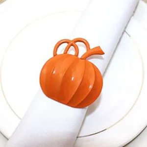 Close-up detail of a bright orange metallic pumpkin napkin ring on a white cloth napkin.
