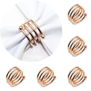 Rose gold metal napkin ring detail showing the elegant spiral double-bead design on white fabric.