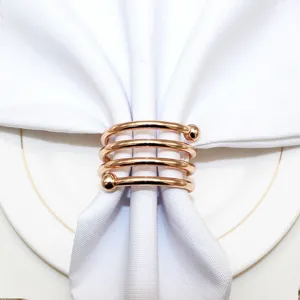 Rose gold metal spiral napkin ring detail, elegant table setting prop for hotel decor.