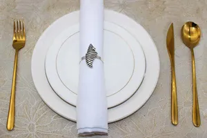 Vintage metal shell napkin ring set with white cloth napkin for elegant dining table decor.