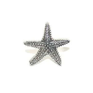 Vintage silver starfish metal napkin ring detail shot, retro marine table decor item.