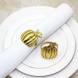 Close-up detail of vintage gold pumpkin napkin ring on white napkin and ceramic plate table decor.