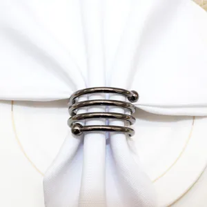 Metal spring napkin ring detail close-up showcasing modern table decor and elegant dining setup.