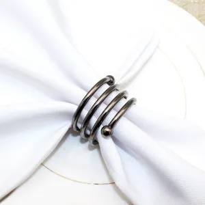 Detail shot of metal spring napkin ring with double beads on white napkin for hotel table decor.