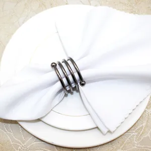 Close up view of metal spring napkin ring with spiral design and double bead ends on table.