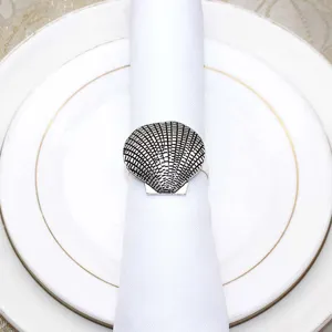 Close-up detail of vintage metal seashell napkin ring holding elegant white fabric napkin.