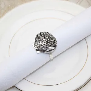 Close up of vintage shell napkin ring on white plate, elegant marine table decor detail.