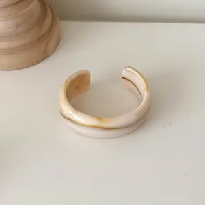 Nahaufnahme des breiten Harz Armreifs mit elegantem Creme und Braun Marmor Muster.