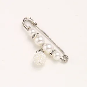 Pearl brooch detail shot showing sparkling rhinestones and elegant pearls on a waist tightening pin.