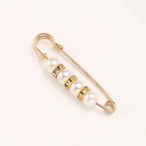 Detail shot of pearl rhinestone safety pin brooch, elegant clothes waist tightening accessory.