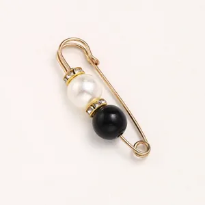 Close-up detail of a pearl and black bead rhinestone waist tightening safety pin brooch.
