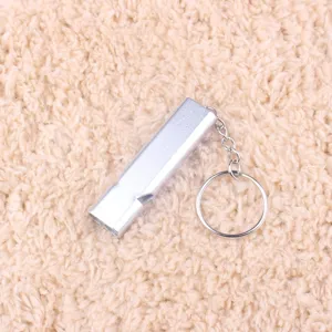 Gros plan sifflet double en metal, outil de survie exterieur portable avec anneau.